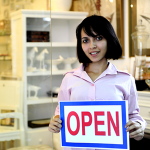 girl holding a sign that says open